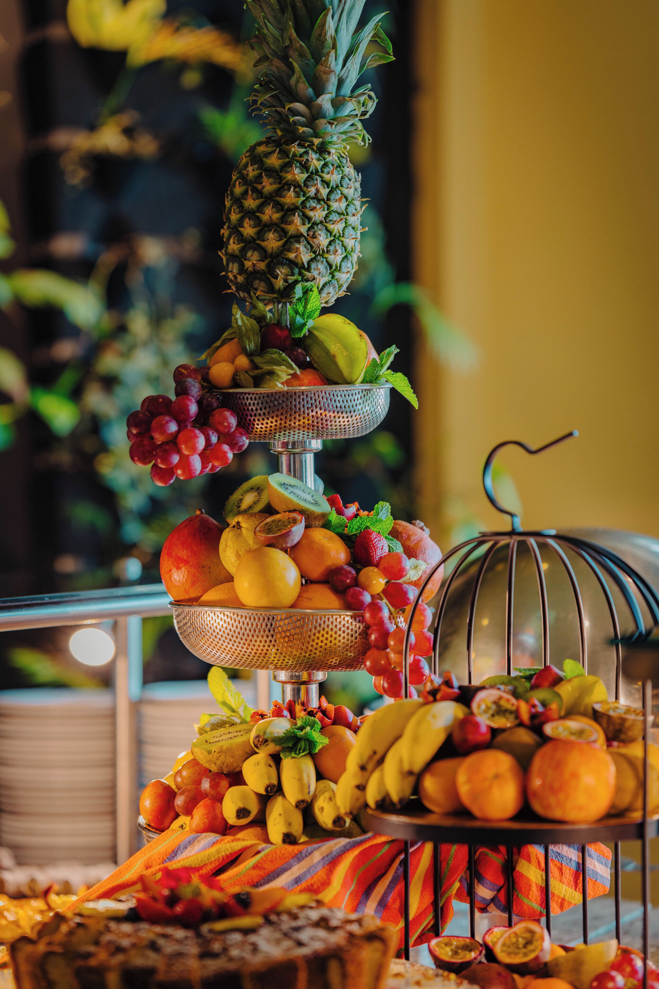 A fruit display with a pineapple, grapes, kiwi, strawberries, and oranges.