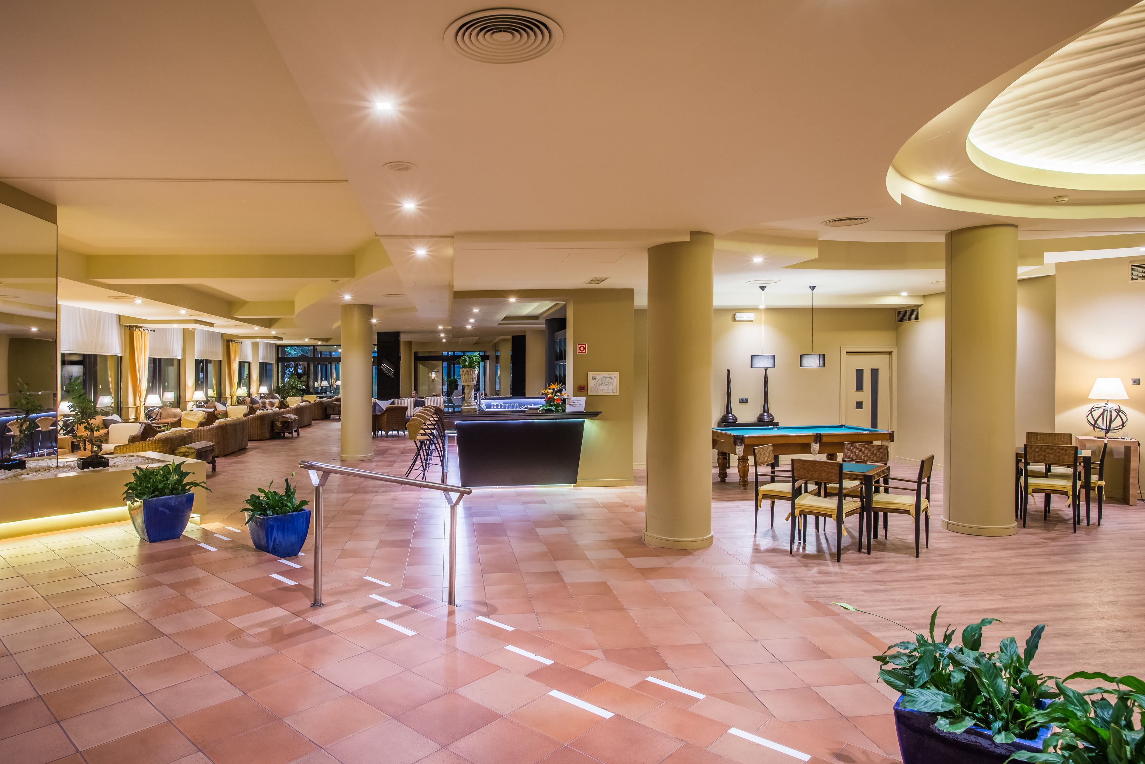 A spacious lobby with a reception desk, seating areas, and a pool table.