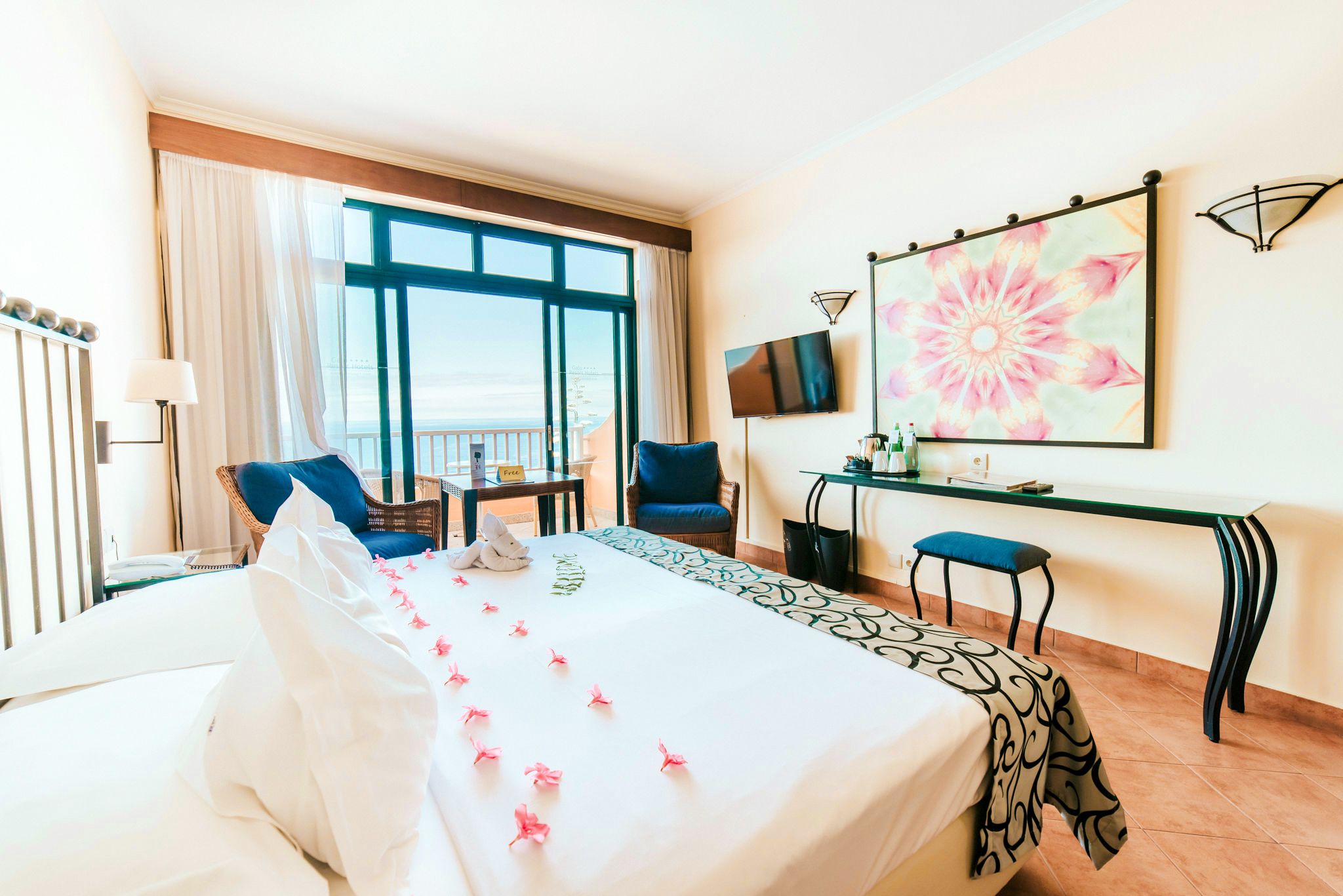 A hotel room with a large bed, a desk, a chair, a TV, and a window with a view.