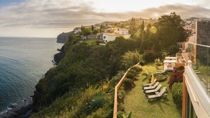 A coastal property with a view of the sea, a garden with lounge chairs, and a hillside with buildings. - Hotel Alpino Atlantico Ayurveda Cure Centre - Adults Only (Santa Cruz)