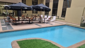 A swimming pool with lounge chairs and umbrellas, surrounded by a building with large windows. - Diego De Almagro Santiago Centro (Santiago)
