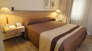 A hotel room with a large bed, two bedside lamps, a nightstand with a phone and notepad, wooden headboard, and framed floral artwork on the wall. - Diego De Almagro Santiago Centro (Santiago)