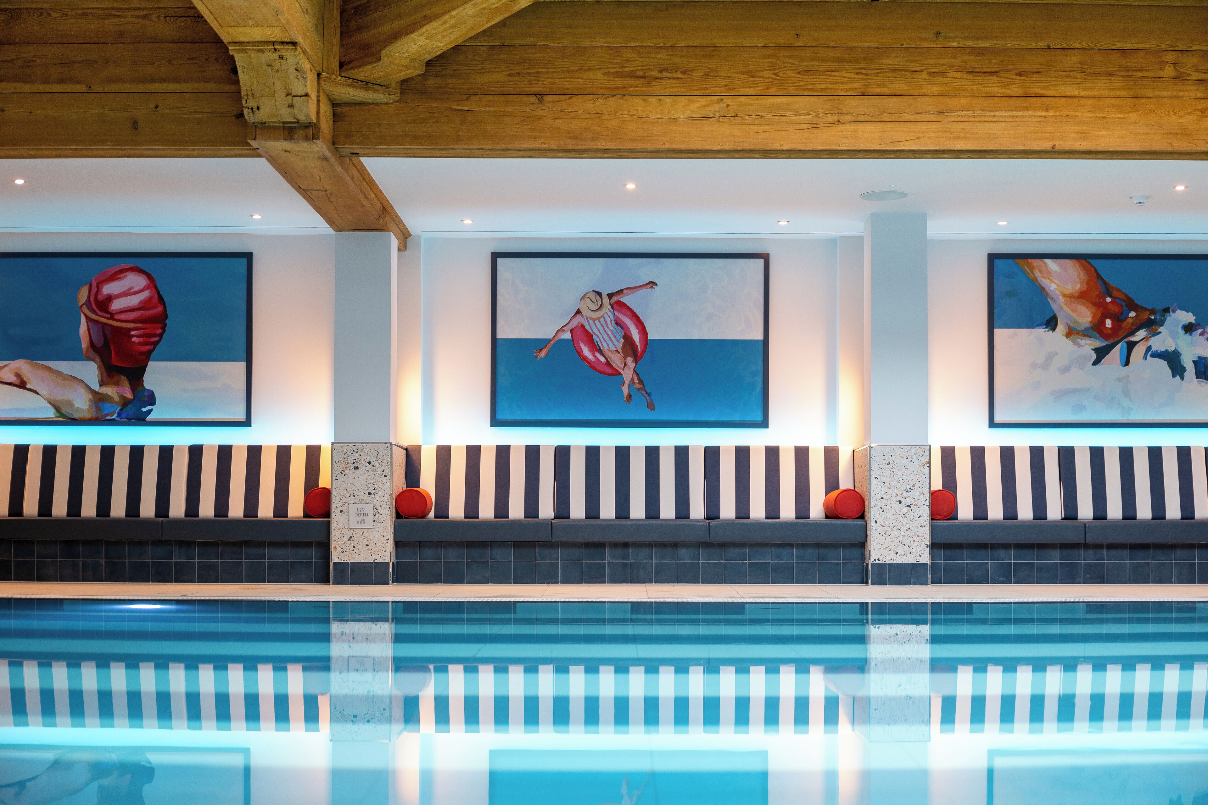 A swimming pool with three large paintings on the wall above it.