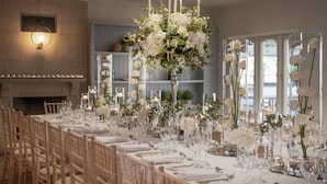 A long dining table set with white tablecloths, glassware, and floral centerpieces. - Solent Hotel and Spa (Fareham)