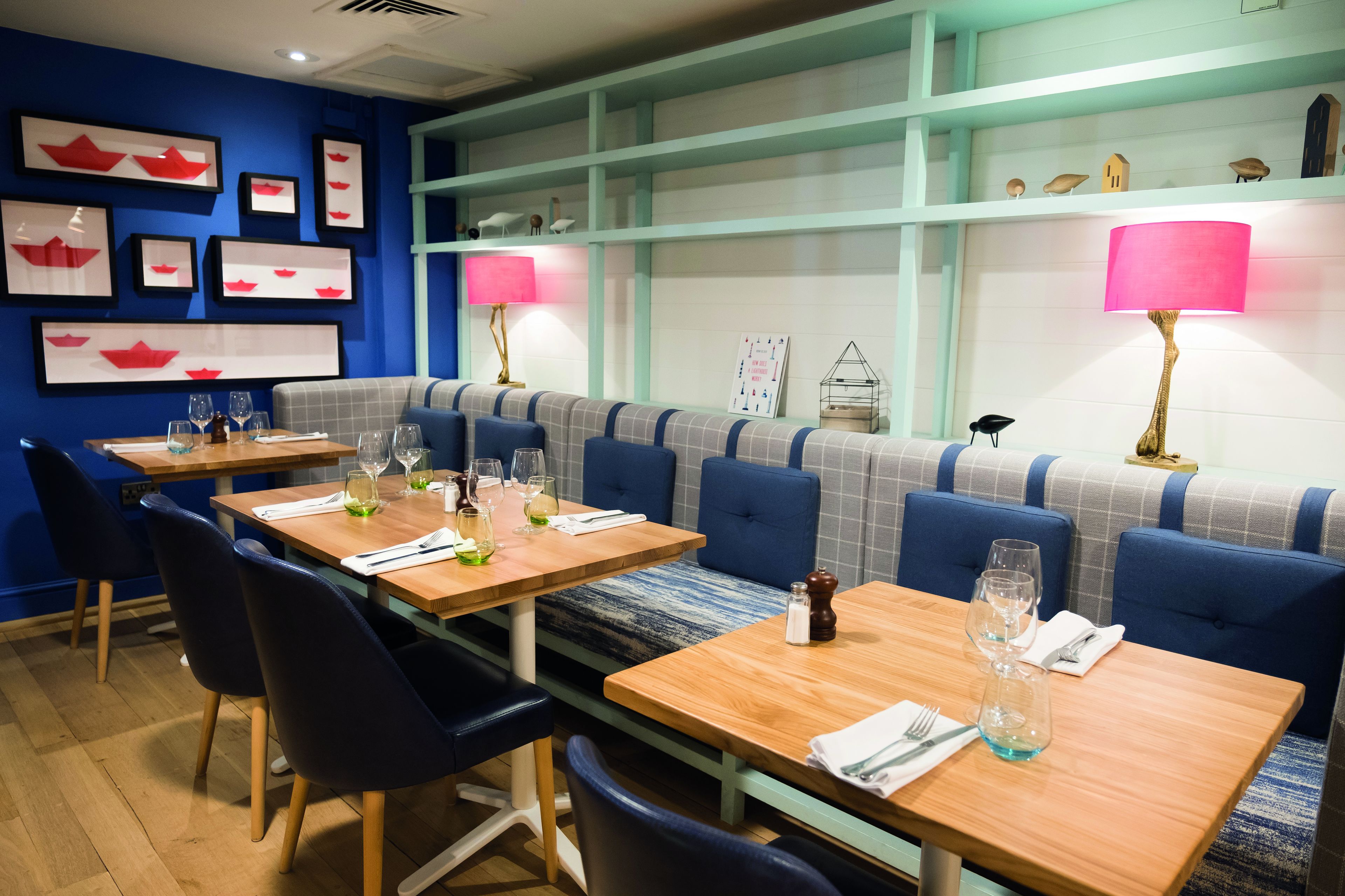 Un restaurante con decoración azul y blanca, mesas de madera y asientos acolchados en azul.