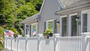 A white building with a balcony, a flag, and a number sign. - Ocean Inn on Nantasket Beach (Hull)