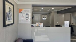 Un espace d’accueil d’hôtel au design moderne, comprenant un comptoir de réception, des œuvres d’art encadrées et un panneau publicitaire faisant la promotion de l’application mobile de l’hôtel.