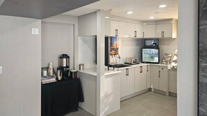 Une cuisine moderne avec des armoires blanches, un comptoir noir et un réfrigérateur.
