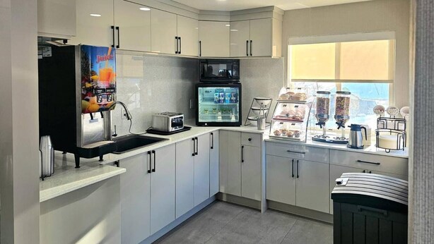 Une cuisine moderne avec des meubles blancs, un four à micro-ondes, un grille-pain et une machine à café.