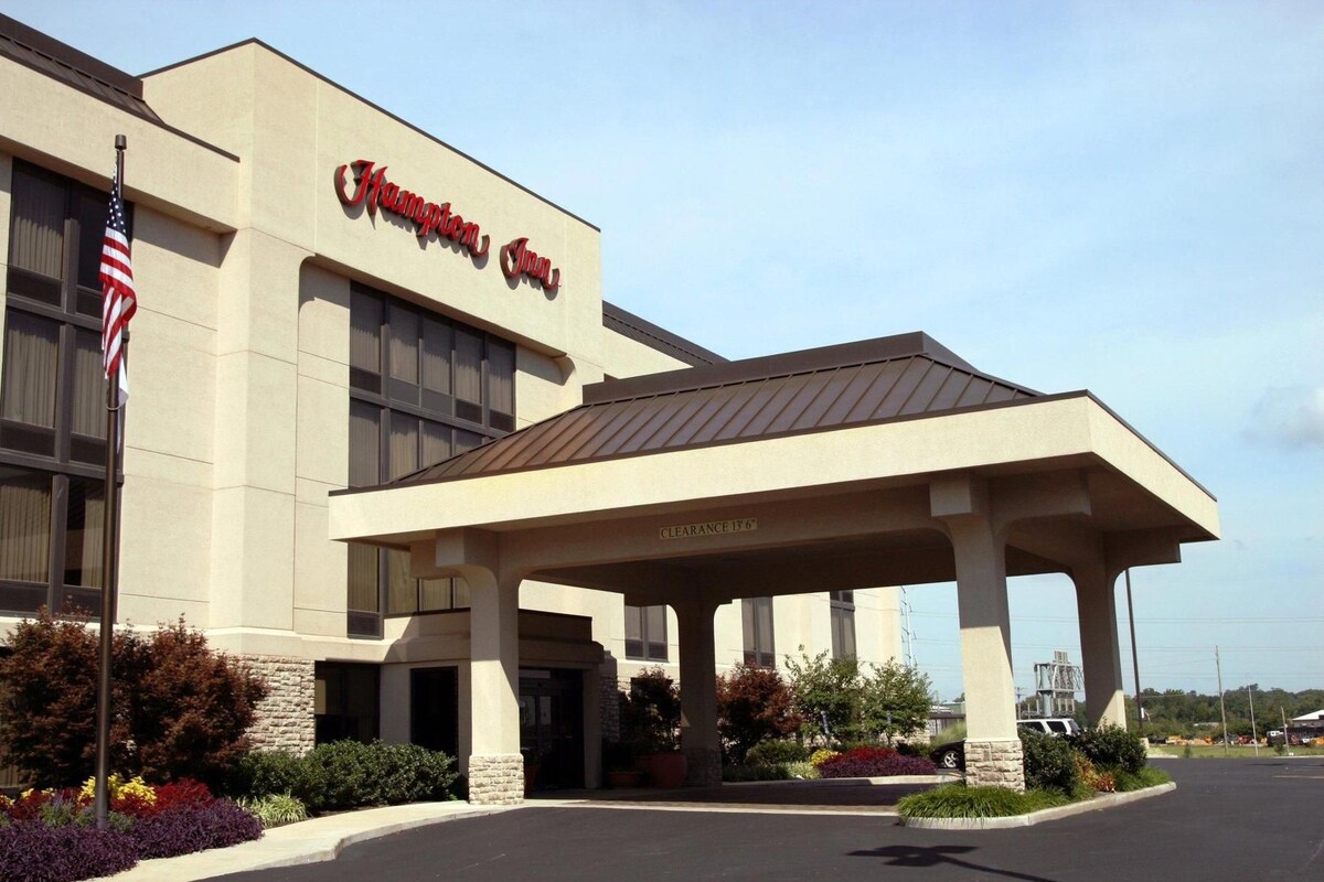 A Hampton Inn hotel with a covered entrance, American flag, and clear signage.