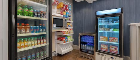 Variedad de dispensadores refrigerados para bebidas y opciones de aperitivos en una tienda.