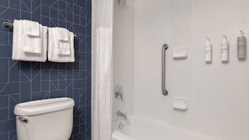 A bathroom with a toilet, a shower with a glass door, and a towel rack with towels.