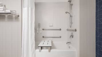 Un baño moderno con bañera, ducha y barras de apoyo.