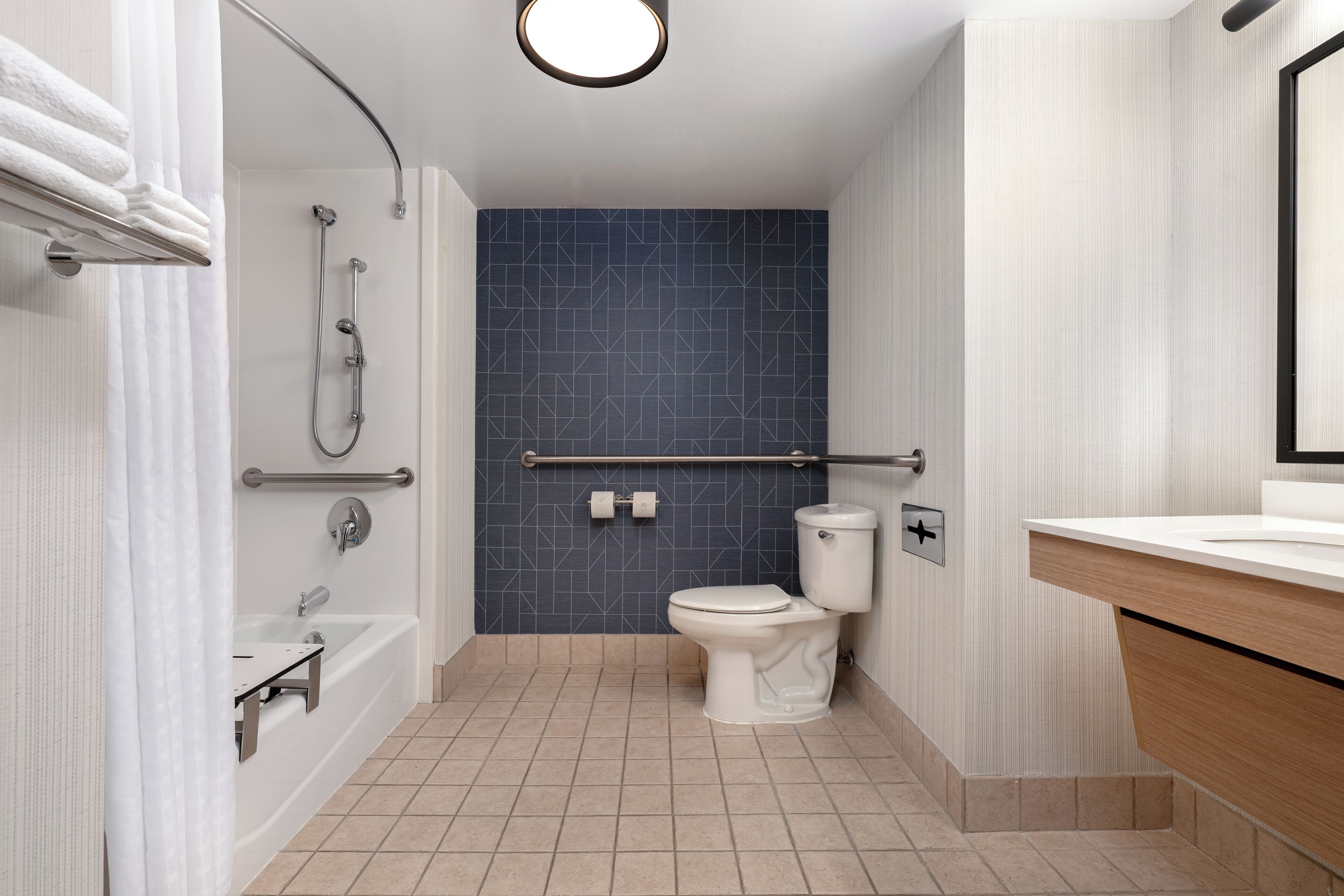 A modern bathroom with a bathtub, shower, toilet, and a vanity with a mirror.