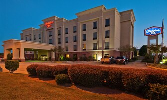 A Hampton Inn hotel with a covered entrance, multiple floors, and a parking area.