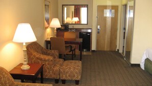 A hotel room with a sofa set, a desk with a lamp, a mirror, and a kitchenette. - Hampton Inn Canton (Canton)