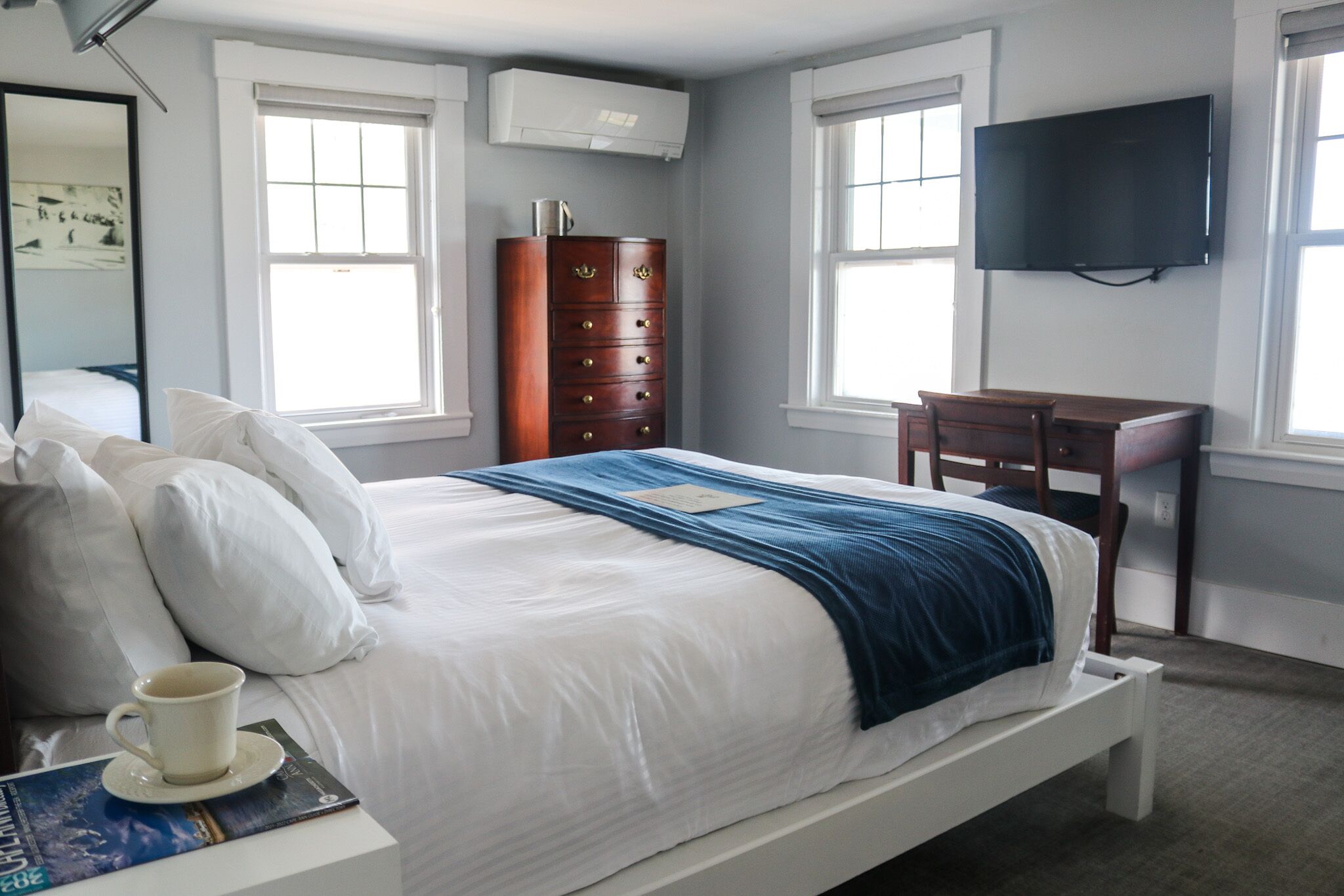 Une chambre à coucher avec un lit, une commode, un bureau et un téléviseur.
