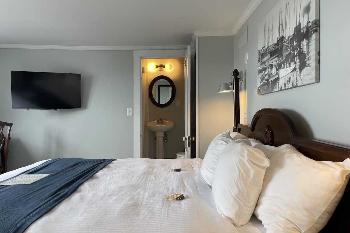 A hotel room with a bed, a television mounted on the wall, a sink, and a mirror.