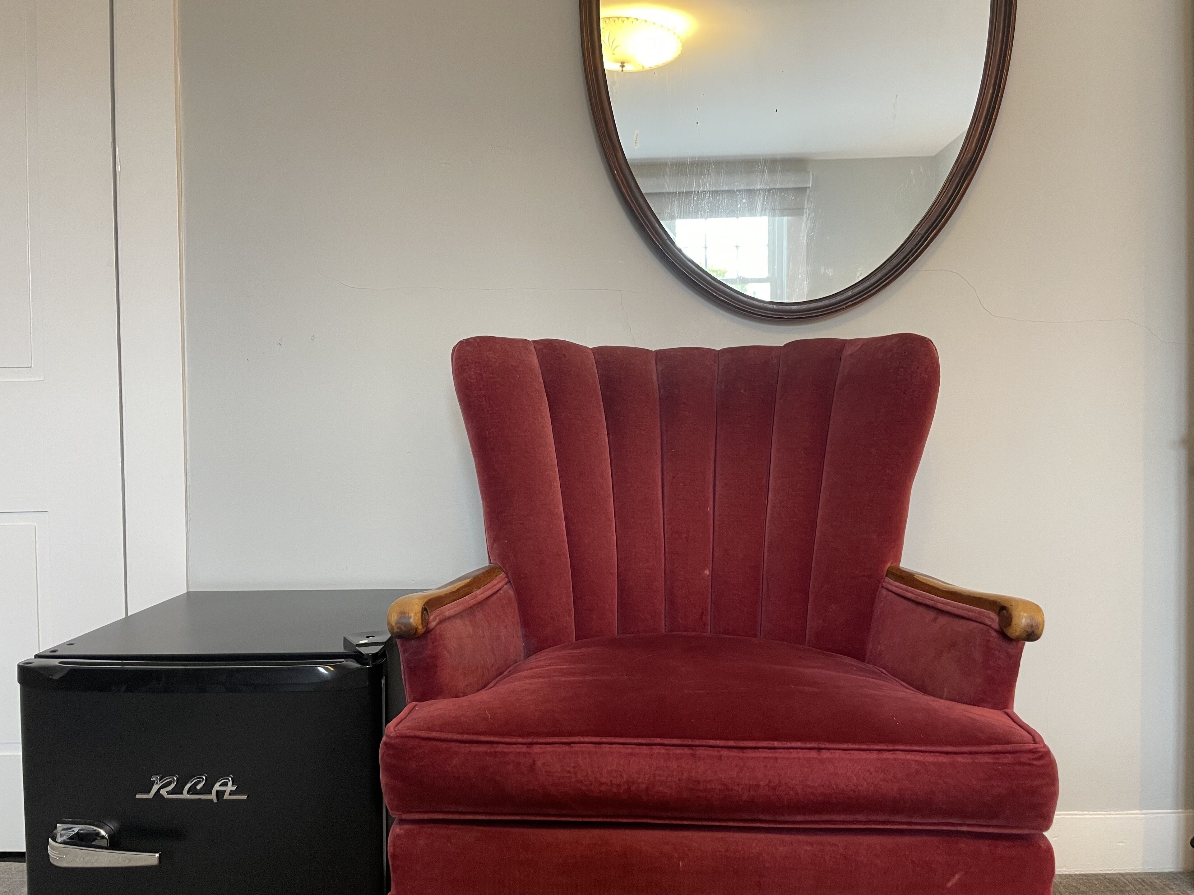 A red velvet armchair with wooden armrests and a black cabinet with the letters "RCA" on it.