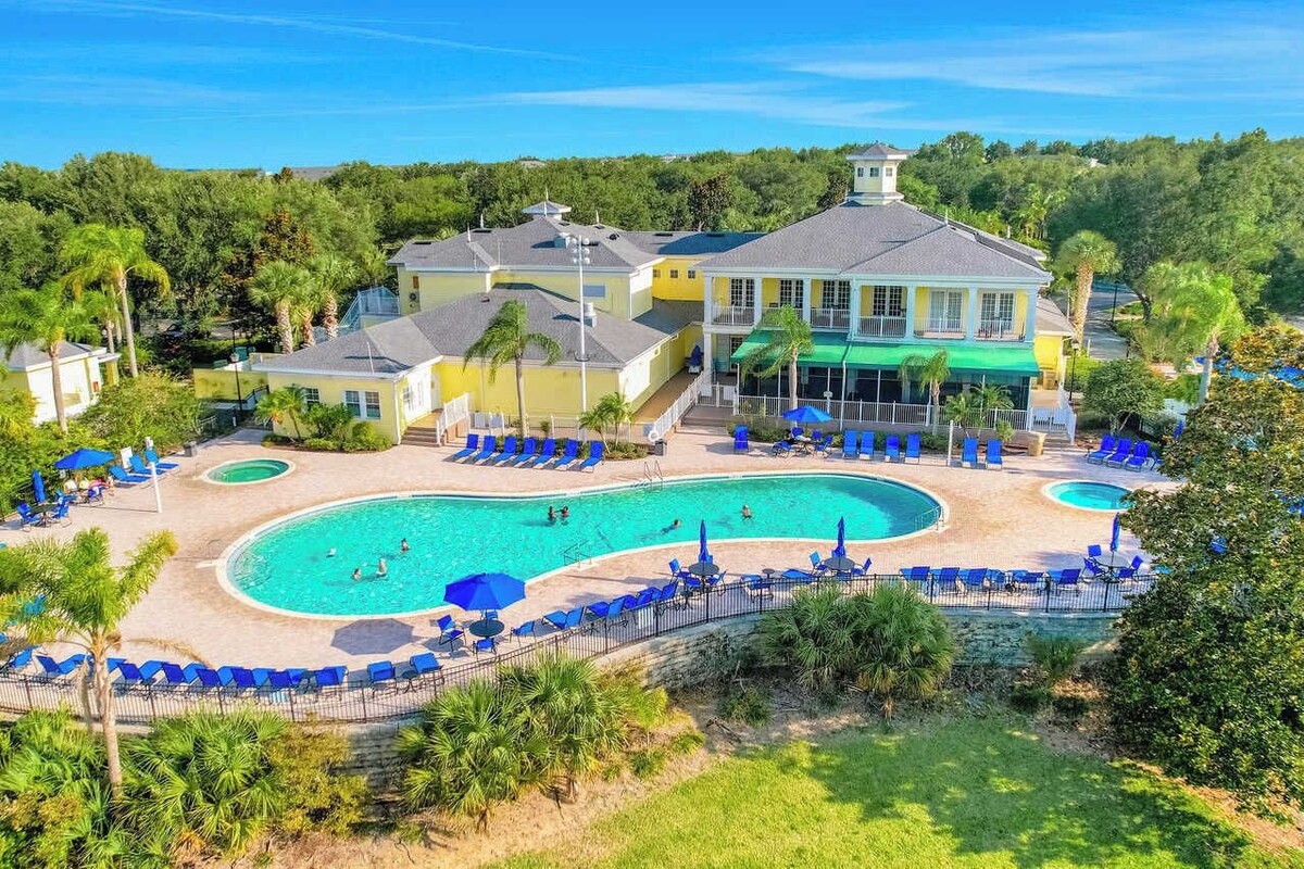 A resort with a large pool, lounge chairs, and a building with a balcony.