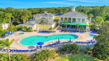 A resort with a large pool, lounge chairs, and a building with a balcony.