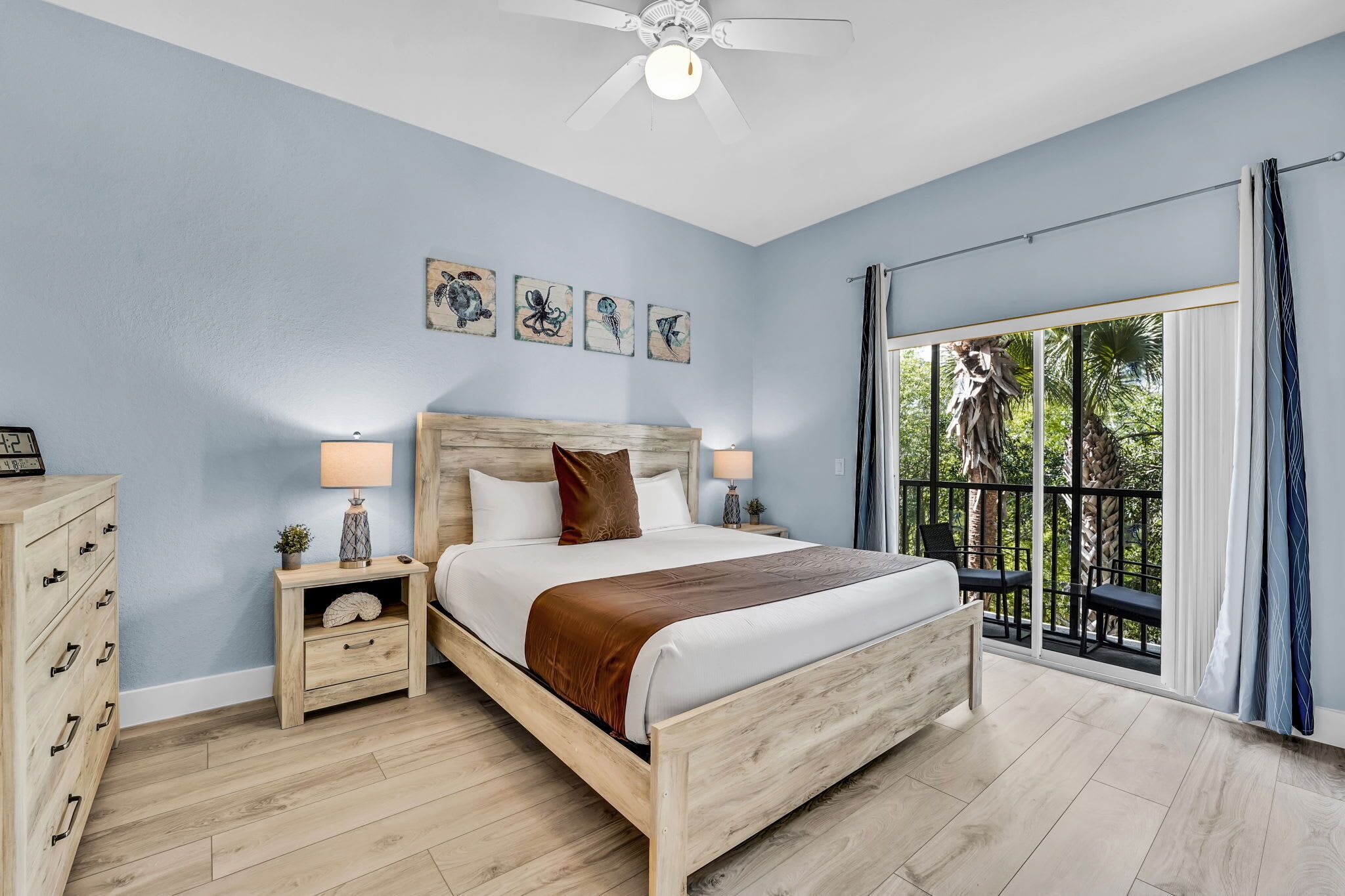 A bedroom with a bed, nightstands, a dresser, and a balcony with a view.