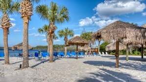 A beach with thatched umbrellas, palm trees, and blue lounge chairs. - Bahama Bay Resort (Davenport)