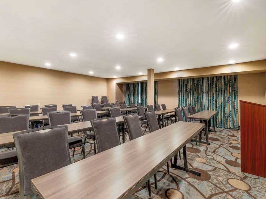 Uma sala de conferência com várias mesas e cadeiras, um púlpito e carpete estampado.