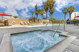 Una piscina al aire libre, sombrillas, sillones reclinables de piscina