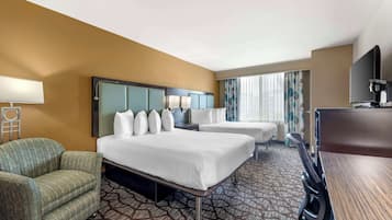 A hotel room with two beds, a desk, a chair, a TV, and a coffee machine.