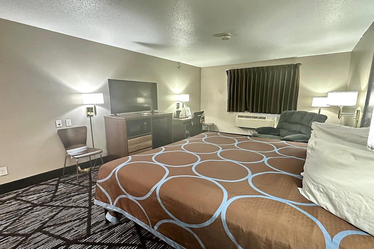 Une chambre d’hôtel avec un grand lit, un bureau, une chaise, une télévision et un appareil de climatisation.