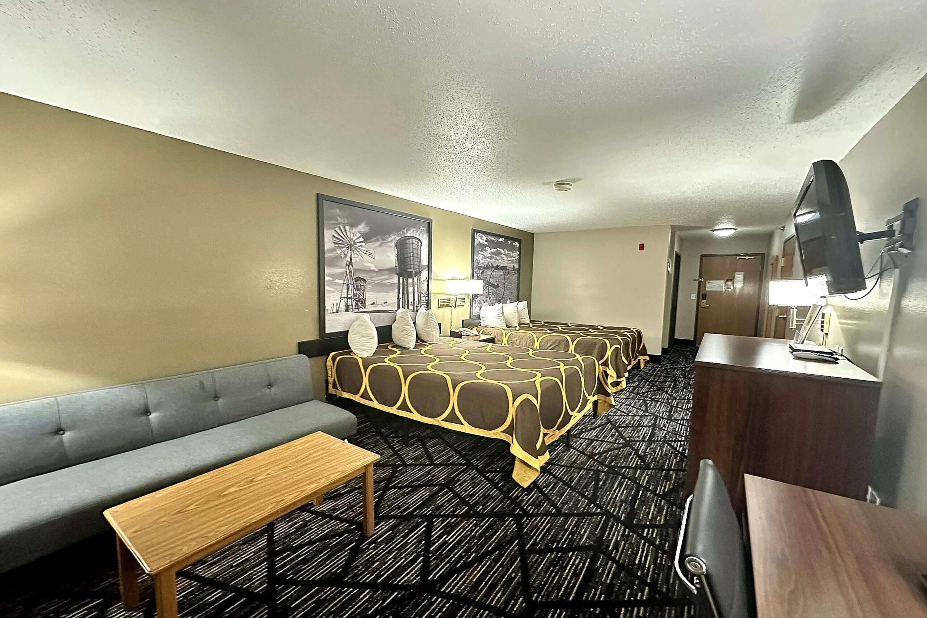 Habitación de hotel con sofá, cama con colcha estampada, escritorio y televisor.