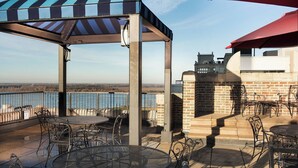An outdoor patio with tables and chairs, a striped awning, and a view of the water. - Residence Inn by Marriott Memphis Downtown (Memphis)