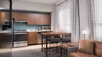 A modern kitchen with stainless steel appliances, wooden cabinets, and a dining area with a sofa and chairs.