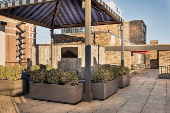 A covered outdoor area with planters and a brick building in the background. - Residence Inn by Marriott Memphis Downtown (Memphis)