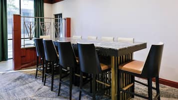 A conference room with a marble table, black chairs with leather seats, and a patterned carpet.
