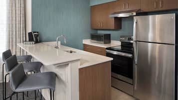 A modern kitchen with a central island, stainless steel appliances, and a seating area with chairs.