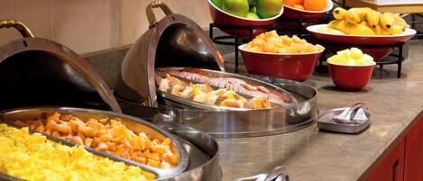 A buffet with various food options including fruits, vegetables, and meats.