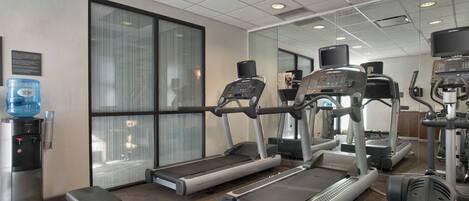 A gym with treadmills, a water dispenser, and exercise equipment.