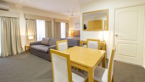 Habitación de hotel con comedor, sofá, cama y espejo.