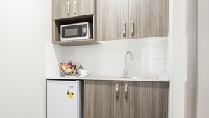 Una kitchenette compacta con microondas, lavamanos y refrigerador.
