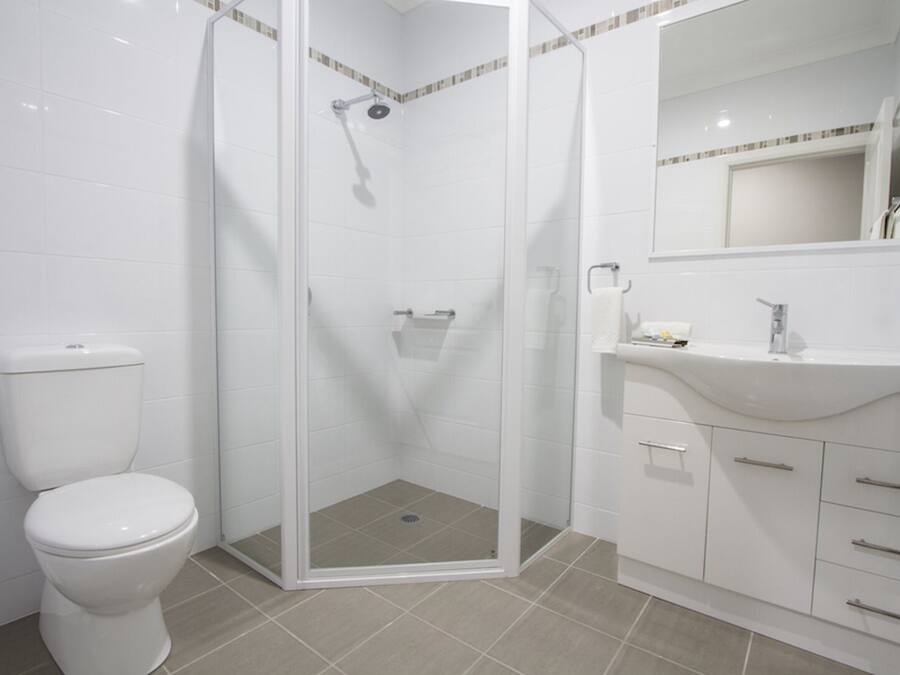 A modern bathroom with a glass-enclosed shower, a white toilet, and a vanity with a mirror.