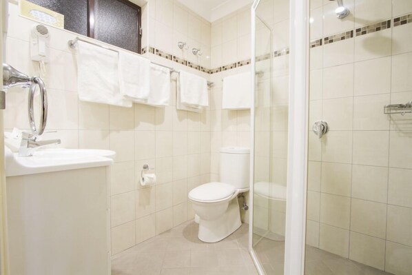 Un baño con inodoro, lavamanos y ducha.