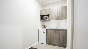Cocina compacta con microondas, refrigerador y armarios de madera.
