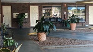 A covered outdoor area with brick walls, potted plants, and a seating area with chairs. - Macintyre Motor Inn (Goondiwindi)