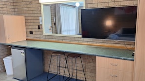 A compact kitchenette with a refrigerator, a sink, a mirror, and two bar stools. - Macintyre Motor Inn (Goondiwindi)