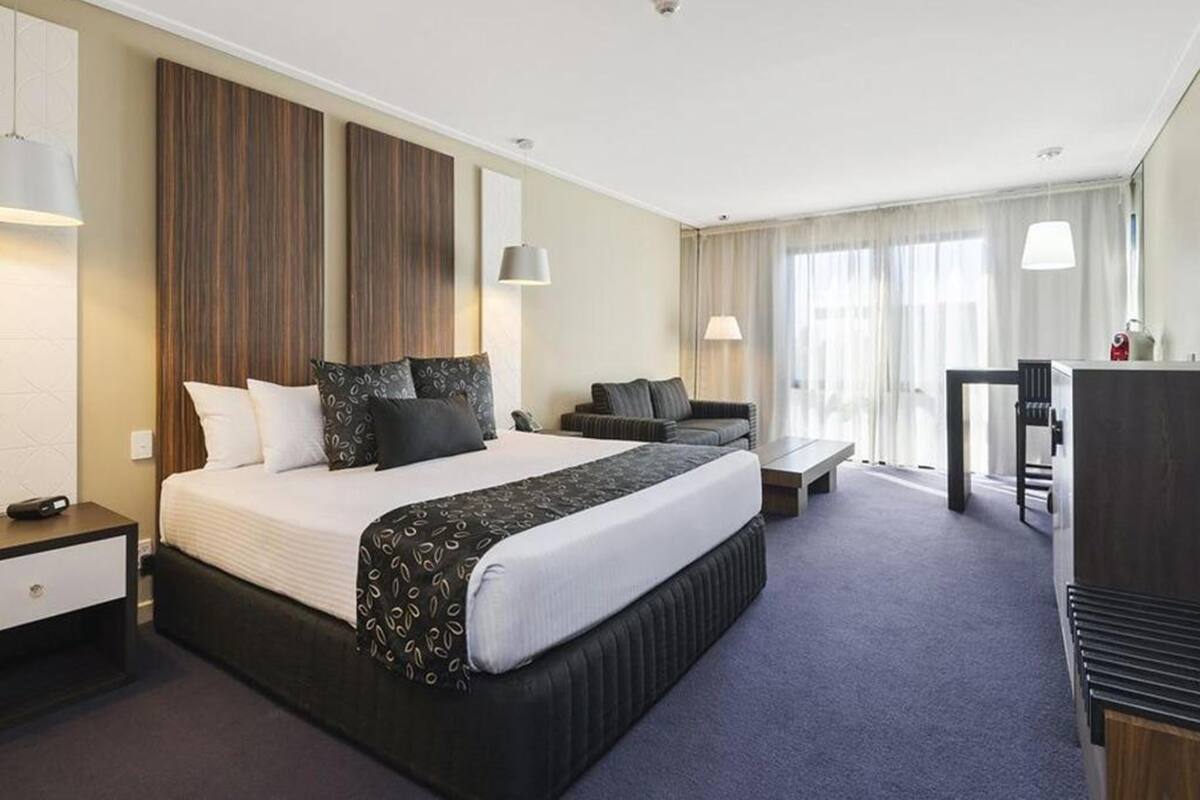 Una habitación de hotel con una cama grande, un escritorio, una silla y un sofá.