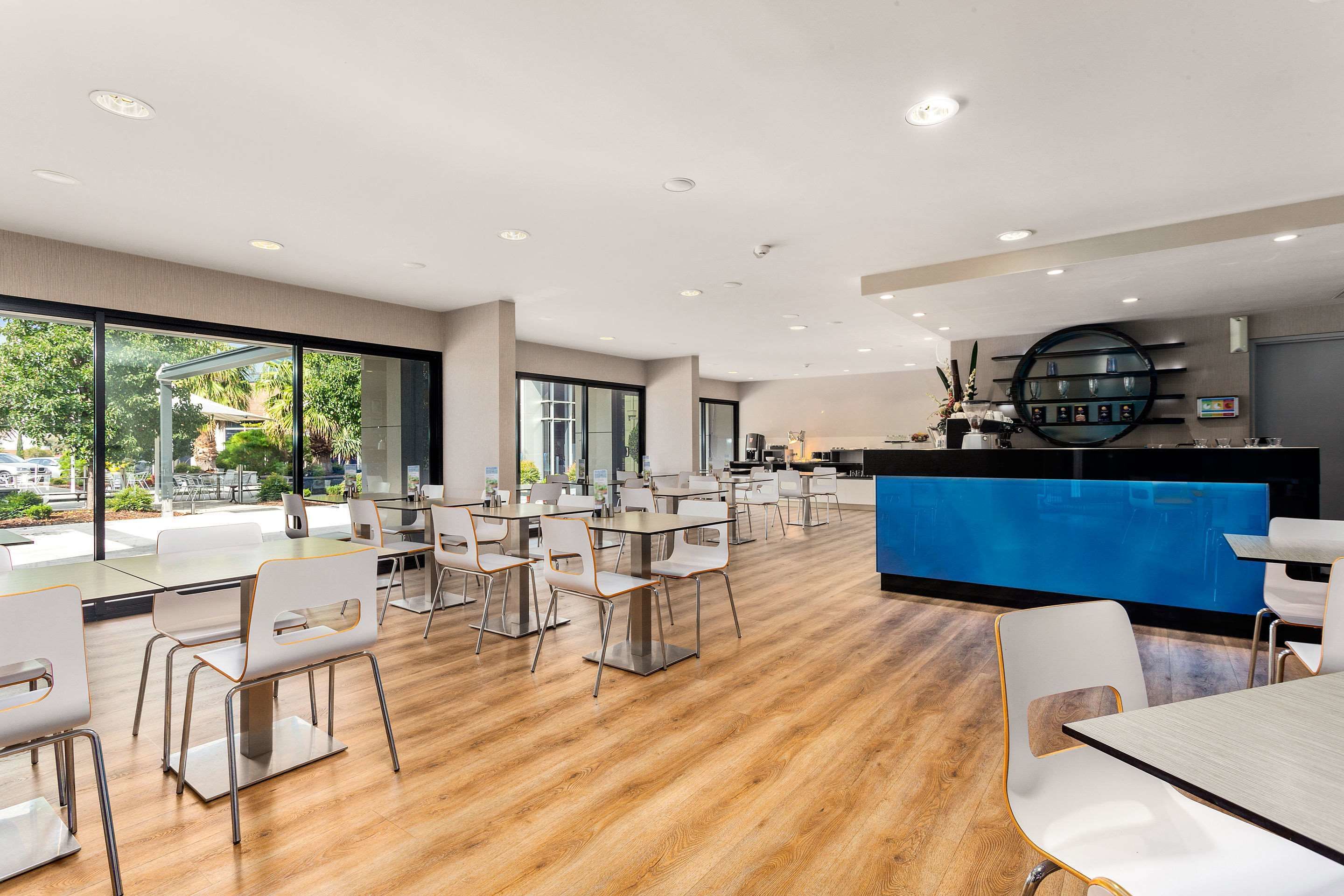 A modern dining area with wooden flooring, white chairs, and a blue counter.