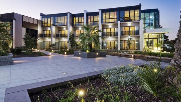 Un hotel moderno a più piani con un'ampia area esterna, finestre ben illuminate e giardini curati.