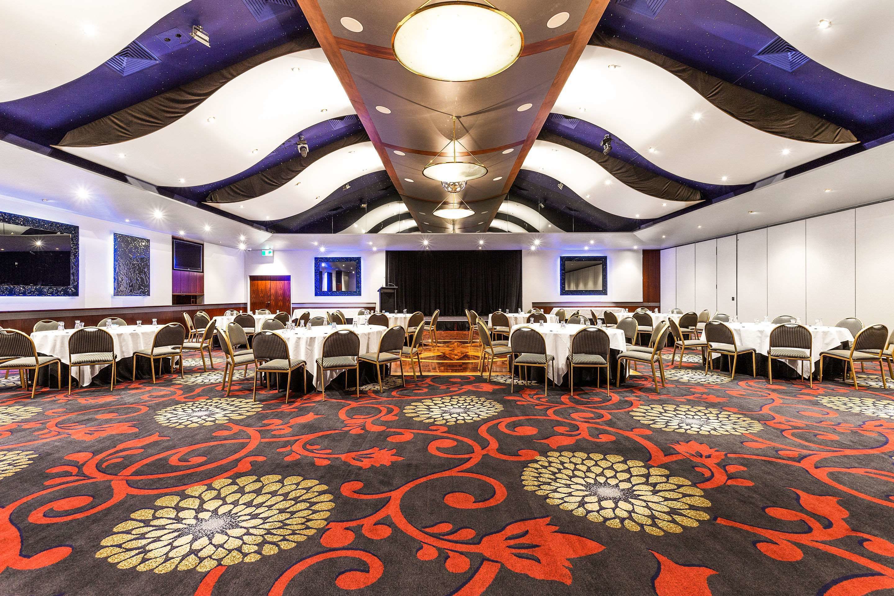 A conference room with round tables, chairs, and a patterned carpet.
